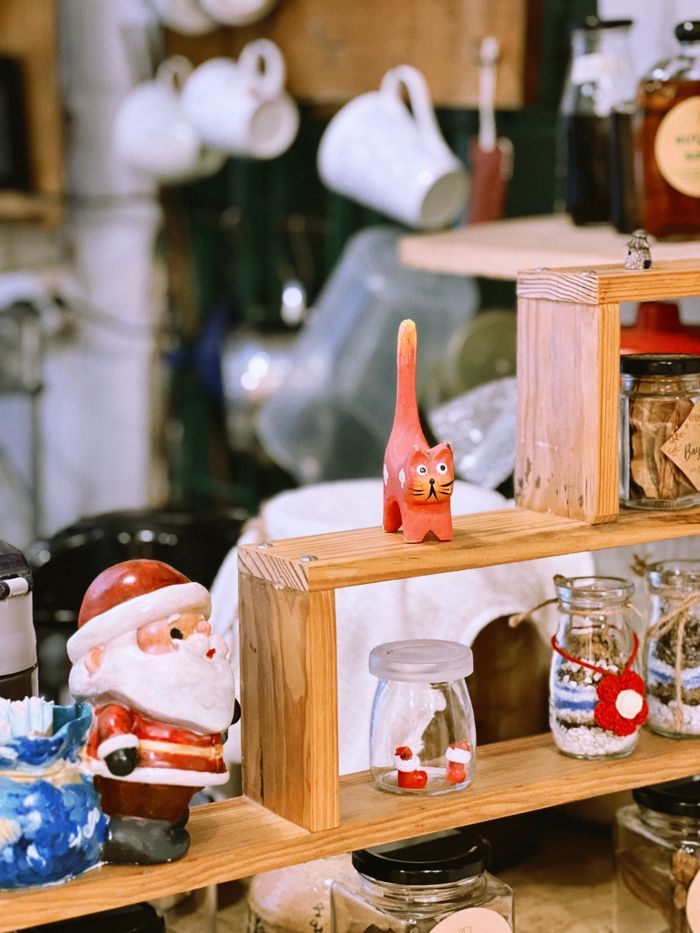 A charming display of handcrafted ceramics featuring a Santa Claus figurine and pottery cat in a cozy shop setting.