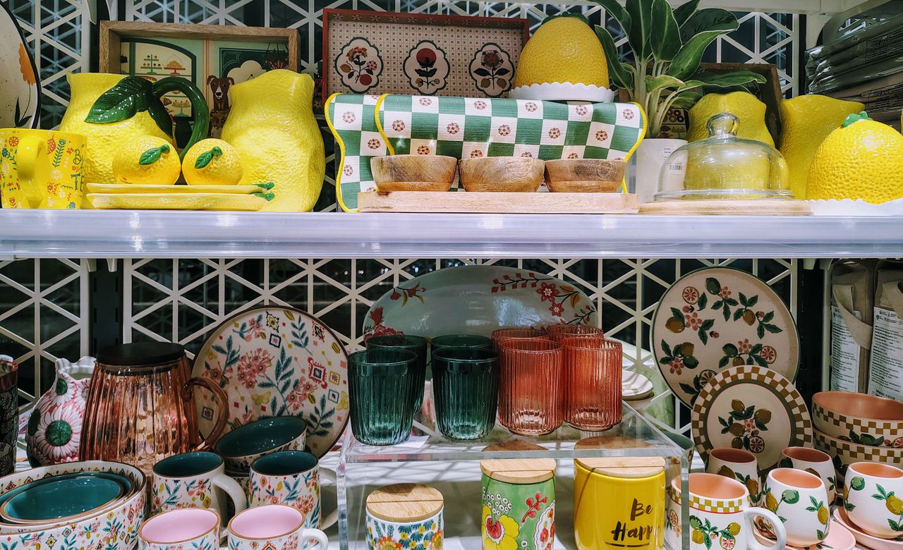 A vibrant collection of ceramic and glassware displayed on shelves, featuring fruit designs and patterns.